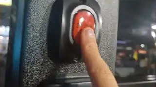 Hand striking red mushroom emergency stop button