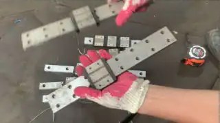 Pink gloved hands arranging white metal small parts