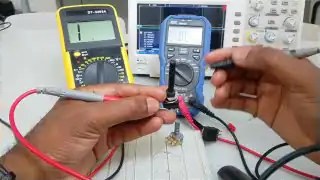 Two hands holding multimeter probes on circuit