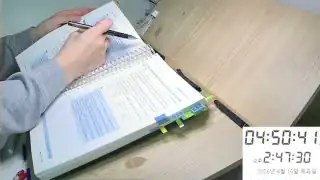 Hand writing in notebook near clipboard