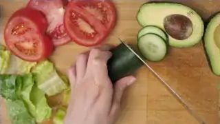 Hand slicing avocado on chopping board