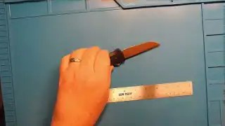 Hand using tape measure on wooden board