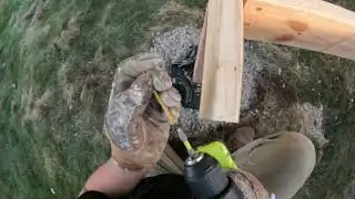 Hands positioning nail gun on timber frame